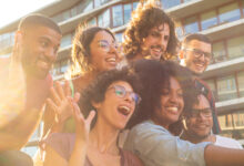 joyful multiethnic friends taking funny group selfie
