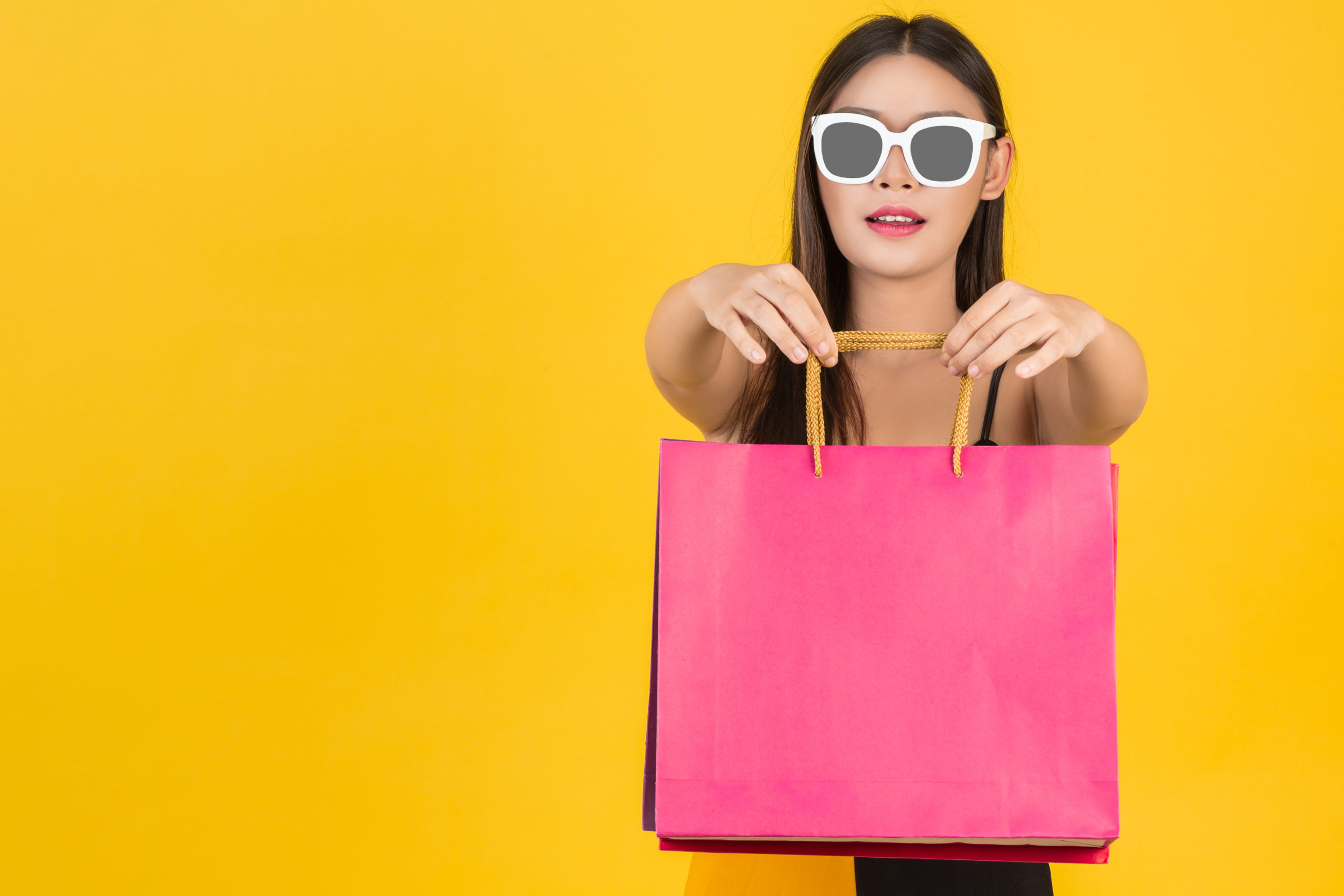 shopping of beautiful women wearing glasses with colorful paper bags on a yellow scaled