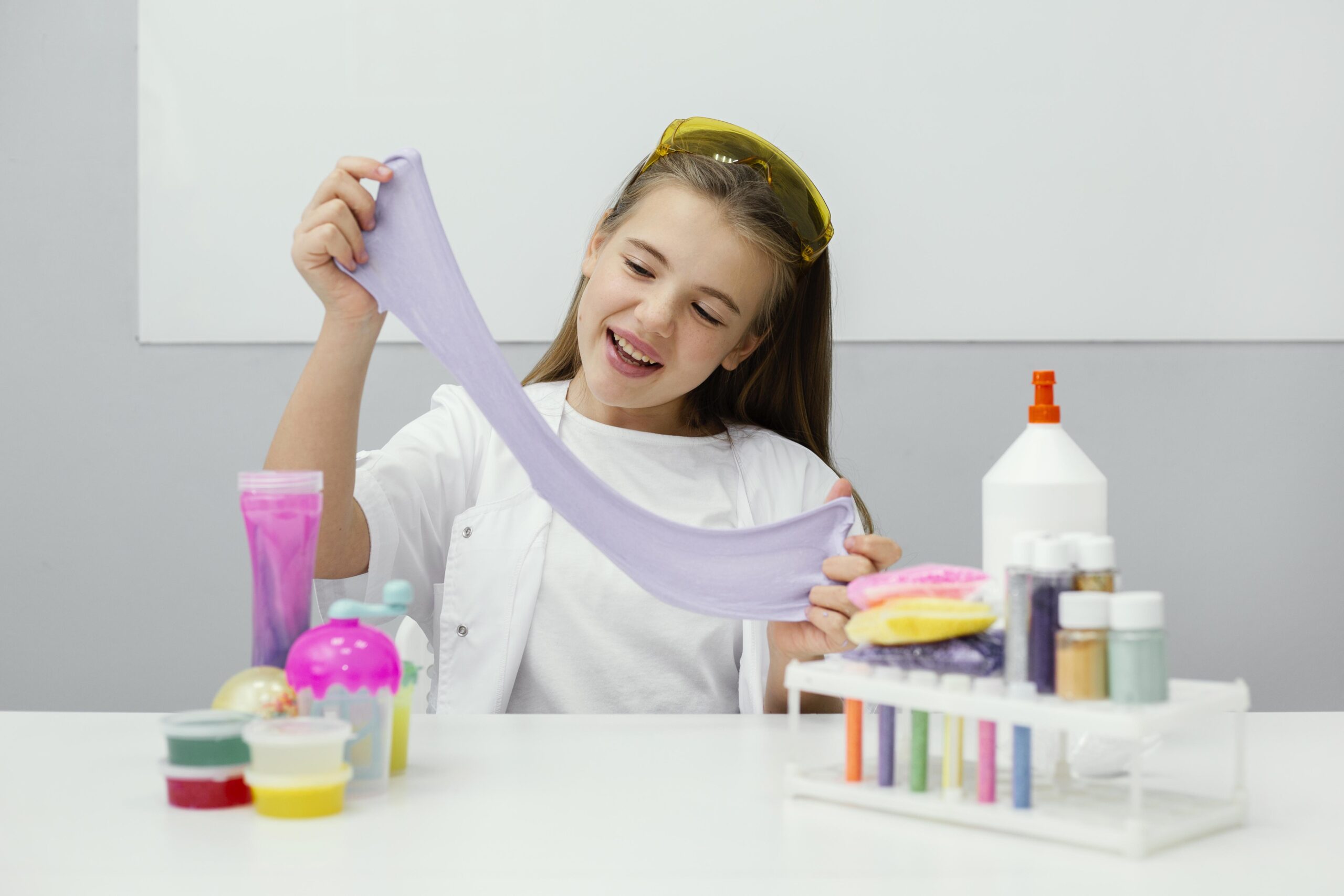 smiley young girl scientist making slime scaled