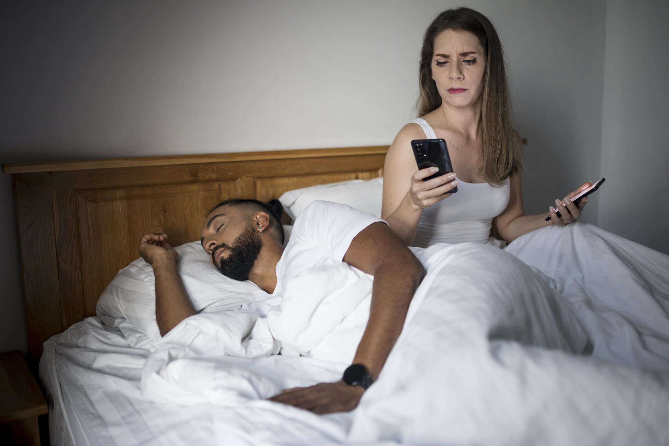 mulher checando o telefone do namorado enquanto dorme scaled